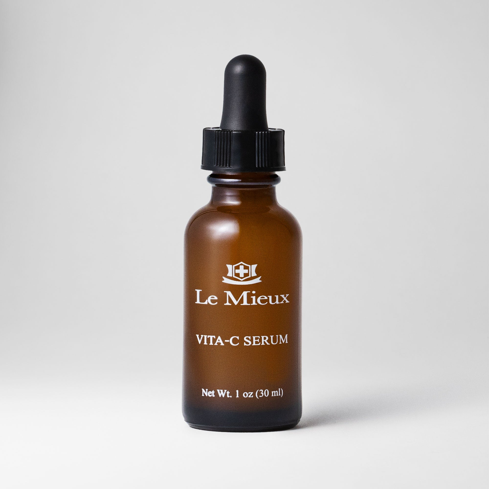 Vita-C Serum 1 oz amber bottle with black dropper lid isolated on a light grey background