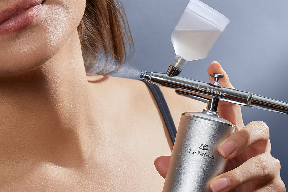 close up of Ionized Oxygen Infuser being held up and sprayed towards neck in front of a blue gray background